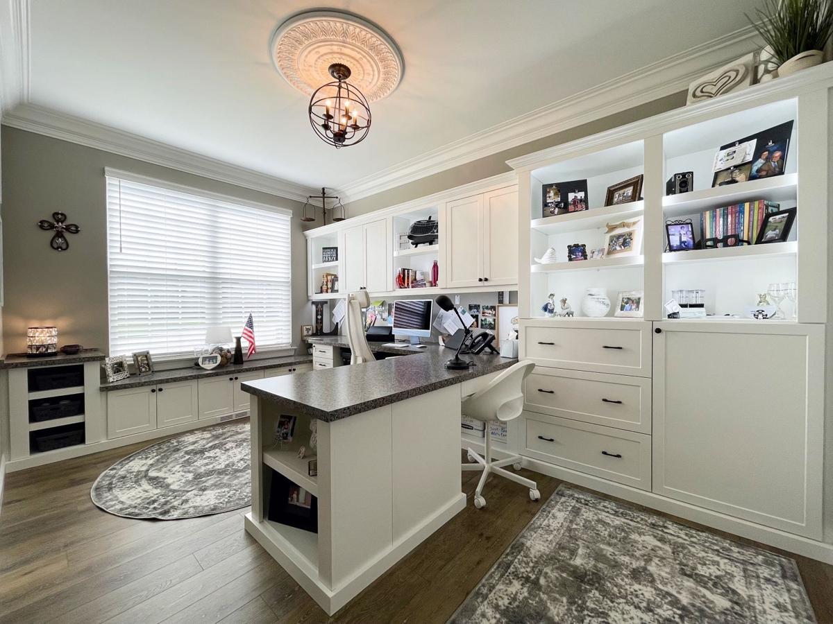 Custom built-in white cabinets, shelving, and desk in a bright home office.