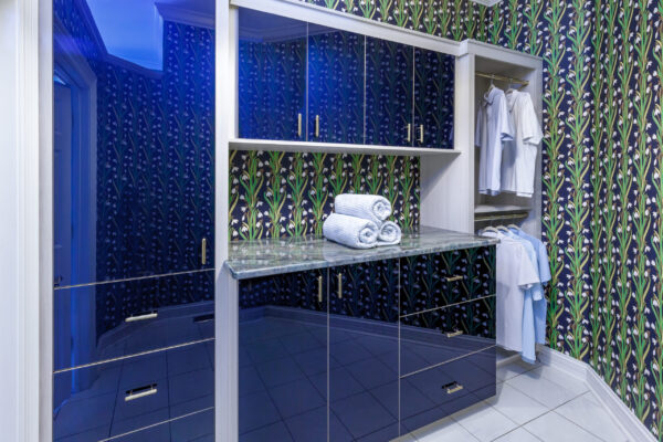 Custom modern closet with blue mirrored cabinets, green marble counter, and "snowdrop" wallpaper.