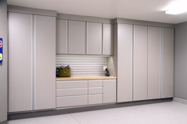 Light gray garage cabinets with a wooden countertop and drawers. A green bag sits on the counter.
