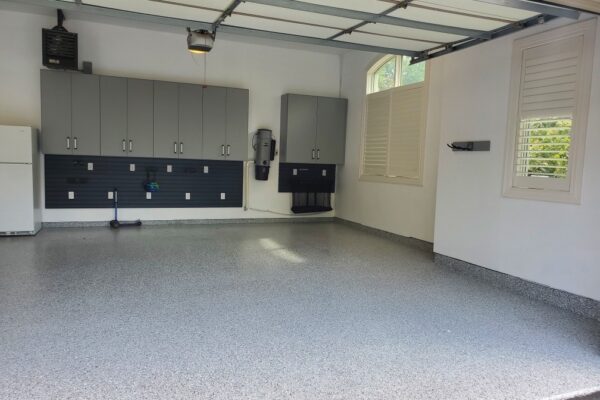 Clean, organized garage with light gray epoxy floor and matching cabinets over a dark gray slat wall.
