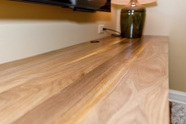 Gleaming wooden countertop with natural grain next to a lamp and TV.