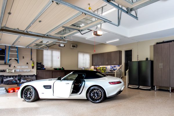 White Mercedes-Benz sports car in a modern, organized garage with light brown cabinets and an epoxy floor.