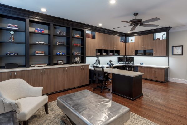 Custom home office with dark wood shelves, light wood cabinets, and two workstations.