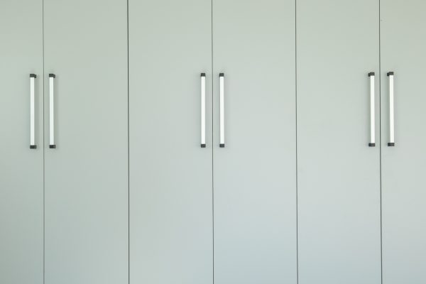 Floor-to-ceiling garage cabinets in light gray with long silver handles, on a gray epoxy floor.